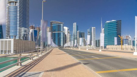 Photo for Panoramic timelapse hyperlapse view of business bay and downtown area of Dubai. Modern skyscrapers and blue sky. Walk on the bridge with traffic on the road - Royalty Free Image