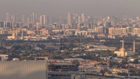 Foto de Vista panorámica de los distritos de Deira y Sharjah en Dubai al atardecer, Emiratos Árabes Unidos. Vista aérea desde la azotea del centro. Deira distrito históricamente ha sido el centro comercial de Dubai y se erige como un puerto - Imagen libre de derechos