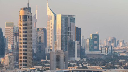 Téléchargez les photos : Dubaï Centre ville au coucher du soleil timelapse. Vue aérienne sur la grande ville futuriste. Skyscrapers of Dubai, Émirats arabes unis. Skyline du soir depuis le toit avec lumière orange réfléchie par la surface en verre - en image libre de droit