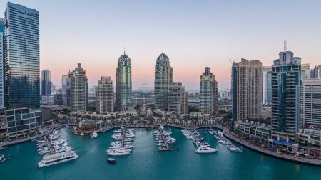Photo for Dubai Marina skyscrapers aerial day to night transition timelapse panorama, port with luxury yachts and marina promenade, Dubai, United Arab Emirates. Illuminated towers and traffic on the road - Royalty Free Image