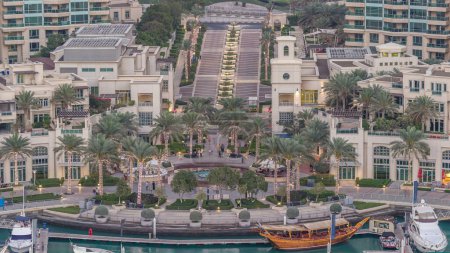 Téléchargez les photos : Dubai Marina fontaine aérienne jour à nuit transition timelapse, port avec des yachts de luxe et promenade de la marina, Dubaï, Émirats arabes unis. Palmiers éclairés et circulation sur la route - en image libre de droit