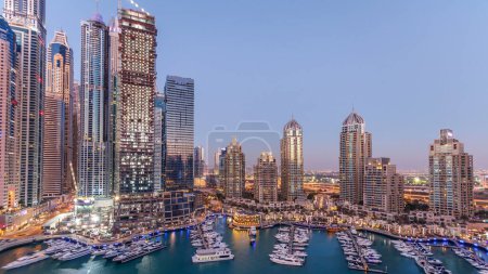 Téléchargez les photos : Dubai Marina skyscrapers aerial day to night transition panoramique timelapse, port avec yachts de luxe et promenade de la marina, Dubaï, Émirats arabes unis. Tours éclairées et circulation sur la route - en image libre de droit