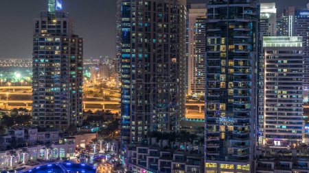 Téléchargez les photos : Dubai Marina avec front de mer la nuit timelapse, lumières scintillantes et gratte-ciel les plus hauts. Tours éclairées et circulation sur la route en arrière-plan - en image libre de droit