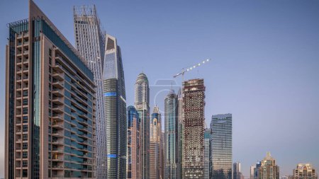 Téléchargez les photos : Vue aérienne des gratte-ciel modernes du jour à la nuit transition timelapse avant le lever du soleil à Dubai Marina avec des yachts à Dubaï, Émirats Arabes Unis. Tours lumineuses le soir - en image libre de droit