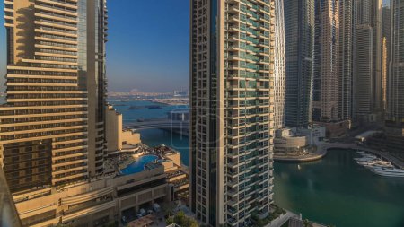 Photo for View of modern skyscrapers shining in sunrise lights timelapse in Dubai Marina with yachts in Dubai, UAE. Rays of lights reflected on glass. - Royalty Free Image