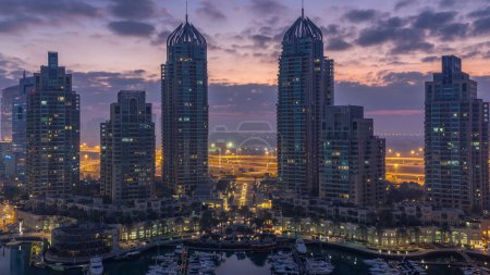 Foto de Vista aérea de rascacielos modernos noche a día timelapse transición antes del amanecer en Dubai Marina con yates en Dubai, Emiratos Árabes Unidos. Torres iluminadas temprano en la mañana - Imagen libre de derechos