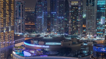 Photo for Night illumination of Dubai Marina and JLT aerial timelapse, UAE. Modern skyscrapers and residential buildings. Traffic on the road. Swimming pool on rooftop - Royalty Free Image