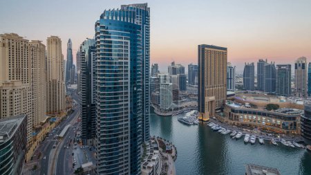 Téléchargez les photos : Soir illumination de Dubai Marina jour à nuit transition aérienne timelapse, EAU. gratte-ciel et bâtiments résidentiels modernes. Yachts et bateaux près du centre commercial sur le canal artificiel ville - en image libre de droit