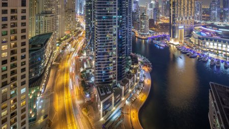 Photo for Night illumination of Dubai Marina and JBR aerial timelapse, UAE. Modern skyscrapers and residential buildings. Traffic on the road and boats with yachts on water - Royalty Free Image