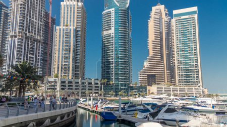 Téléchargez les photos : Dubai baie de la marina avec des yachts et des bateaux timelapse. Les gratte-ciel les plus hauts reflétés dans l'eau du canal. Ciel bleu au soleil - en image libre de droit
