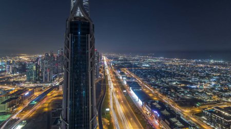 Foto de Dubai Downtown rascacielos noche timelapse modernas torres vista panorámica desde la parte superior en Dubai, Emiratos Árabes Unidos. Tráfico en la carretera Sheikh Zayed cerca del canal de agua - Imagen libre de derechos