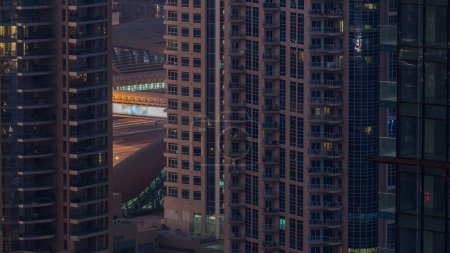 Téléchargez les photos : Skyline de Dubaï avec des gratte-ciel nuit à jour timelapse transition à Dubai Marina d'en haut. Vue aérienne. Trafic routier et station de métro - en image libre de droit