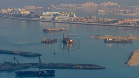 Foto de Vista aérea de Palm Jumeirah durante el amanecer timelapse desde una azotea, Dubai, Emiratos Árabes Unidos. Trabajos de construcción con excavadoras y embarcación en primer plano temprano en la mañana - Imagen libre de derechos
