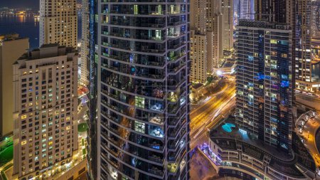 Téléchargez les photos : Illumination nocturne de Dubai Marina et JBR aerial timelapse, EAU. gratte-ciel et bâtiments résidentiels modernes. Trafic sur la route et fenêtres éclatantes - en image libre de droit