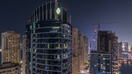 Foto de Iluminación nocturna de Dubai Marina y JBR timelapse aéreo, Emiratos Árabes Unidos. Rascacielos modernos y edificios residenciales. Tráfico en la carretera y ventanas brillantes - Imagen libre de derechos