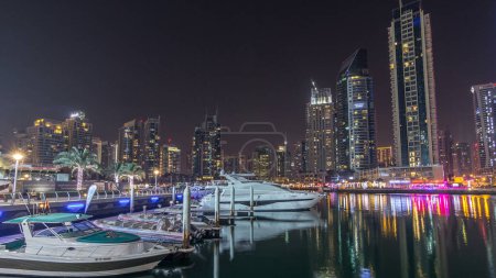 Téléchargez les photos : Dubai baie de la marina avec des yachts et des bateaux timelapse hyperlapse. gratte-ciel éclairés par la nuit réfléchis dans l'eau du canal - en image libre de droit