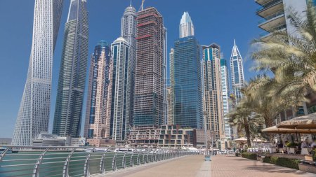 Foto de Vista panorámica con rascacielos modernos, pasarela y yates de Dubai Marina timelapse, vista desde el terraplén en el día soleado. Emiratos Árabes Unidos - Imagen libre de derechos