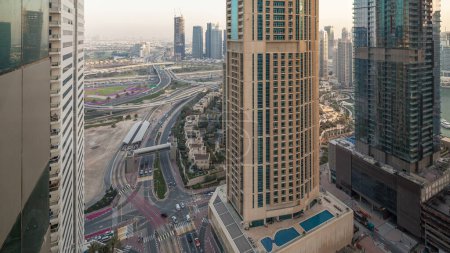 Téléchargez les photos : Vue aérienne d'une intersection de la route et des tours modernes dans une grande ville passage du jour à la nuit timelapse. Paysage urbain du quartier Marina de Dubaï aux EAU avec voitures et gratte-ciel
. - en image libre de droit