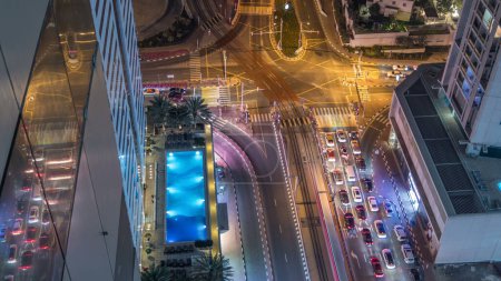 Foto de Vista aérea de una intersección de carreteras en un gran lapso de tiempo nocturno de la ciudad. Paisaje urbano del distrito de Dubai Marina en Emiratos Árabes Unidos con coches y rascacielos y línea de tranvía
. - Imagen libre de derechos