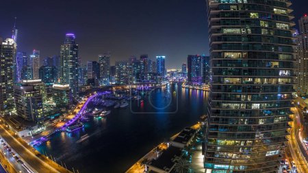 Photo for Water canal on Dubai Marina skyline at night timelapse. Residential towers with lighting and illumination. Floating yachts and boats with traffic near skyscrapers - Royalty Free Image