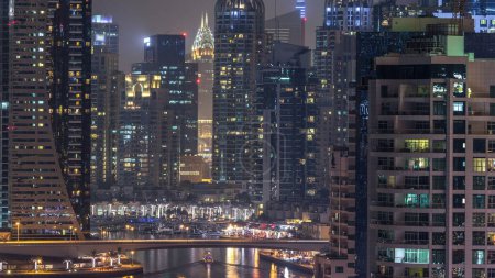 Téléchargez les photos : Canal d'eau et promenade sur Dubai Marina skyline la nuit timelapse. Tours résidentielles avec éclairage et éclairage. Yachts flottants et bateaux avec trafic près des gratte-ciel - en image libre de droit