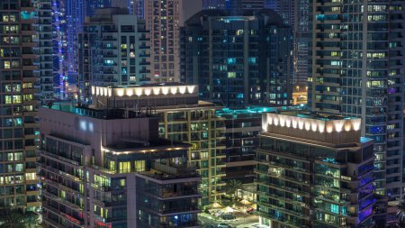 Téléchargez les photos : Tours résidentielles avec éclairage et éclairage timelapse. Route et promenade sur Dubai Marina et JLT skyline la nuit. Trafic près des gratte-ciel avec des fenêtres éclatantes - en image libre de droit