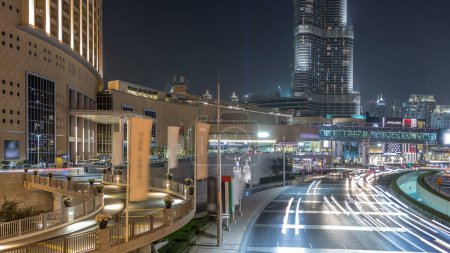 Foto de Tráfico de coches en la carretera cerca del centro comercial por la noche en el centro de timelapse. Rascacielos con iluminación nocturna. Vista superior desde el puente. Dubai, Emiratos Árabes Unidos - Imagen libre de derechos