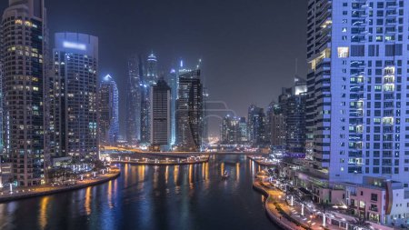 Téléchargez les photos : Canal d'eau et promenade sur Dubai Marina skyline la nuit timelapse panoramique. Tours résidentielles avec éclairage et éclairage. Yachts flottants et bateaux avec trafic près des gratte-ciel - en image libre de droit