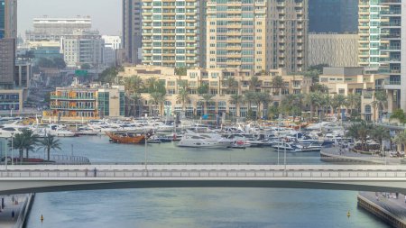 Téléchargez les photos : Pont à Dubai Marina Skyline pendant le coucher du soleil timelapse. Grande perspective de plusieurs gratte-ciel les plus hauts avec des yachts et des bateaux. Lumière du soleil sur les bâtiments. Émirats arabes unis. - en image libre de droit