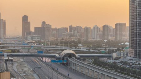 Téléchargez les photos : Vue aérienne des tours Jumeirah lacs gratte-ciel et le quartier Al Barsha pendant le lever du soleil avec la circulation sur la route cheikh zayed et la ligne de métro. Vue sur le toit depuis le port de plaisance de Dubaï avec matin léger temps brumeux - en image libre de droit