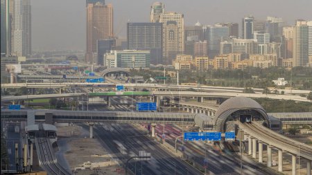 Téléchargez les photos : Vue aérienne des tours Jumeirah lacs gratte-ciel et Al Barsha quartier timelapse avec la circulation sur cheikh zayed route et ligne de métro. Temps de coucher de soleil avec de longues ombres et des reflets sur un verre - en image libre de droit