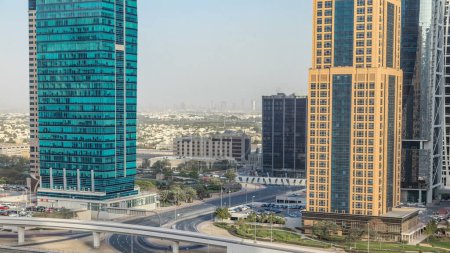 Photo for Aerial view of Jumeirah lakes towers skyscrapers during all day timelapse with traffic on sheikh zayed road and metro line. - Royalty Free Image