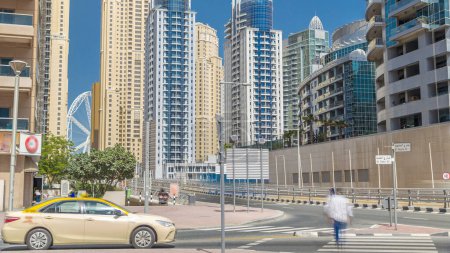 Téléchargez les photos : Dubai Marina avec gratte-ciel timelapse et la circulation dans la rue près du pont routier en béton à travers le canal. Journée ensoleillée avec ciel bleu. Dubai, Émirats arabes unis
. - en image libre de droit