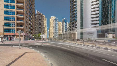 Téléchargez les photos : Dubai Marina avec gratte-ciel intemporel hyperlapsus et la circulation dans la rue sur le pont routier en béton à travers le canal avec des rails de tramway. Journée ensoleillée avec ciel bleu. Dubai, Émirats arabes unis
. - en image libre de droit