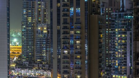 Téléchargez les photos : Tours résidentielles avec éclairage et éclairage timelapse. Fenêtres éclatantes dans Dubai Marina et JLT skyline la nuit. Trafic près des gratte-ciel avec des fenêtres éclatantes - en image libre de droit