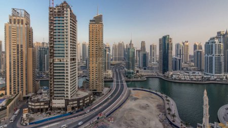 Téléchargez les photos : Vue aérienne de jour comme de nuit sur la promenade et le canal de la marina de Dubaï avec des yachts flottants et des bateaux après le coucher du soleil à Dubaï, Émirats arabes unis. Tours modernes et circulation routière - en image libre de droit