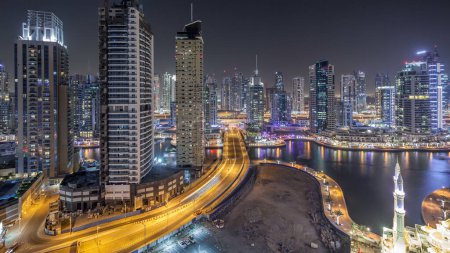 Téléchargez les photos : Tours résidentielles avec éclairage et éclairage timelapse. Canal d'eau et promenade sur Dubai Marina skyline la nuit. Yachts flottants et bateaux avec trafic près des gratte-ciel - en image libre de droit