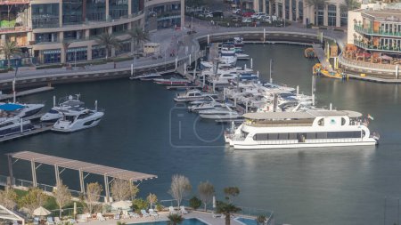 Téléchargez les photos : Promenade et canal à Dubai Marina avec des gratte-ciel de luxe et des yachts autour de timelapse, Émirats arabes unis. Vue aérienne du port au coucher du soleil - en image libre de droit