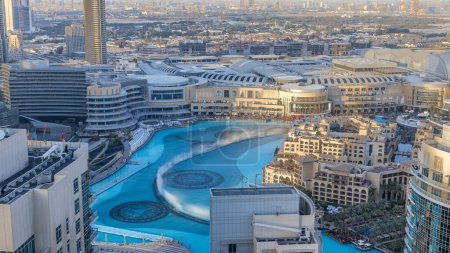 Téléchargez les photos : Vue aérienne du soir Fontaines dansantes au centre-ville et dans un timelapse de lac artificiel au coucher du soleil à Dubaï, Émirats arabes unis. Quartier de la vieille ville - en image libre de droit