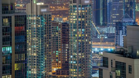 Photo for Dubai downtown night timelapse, illuminated luxury modern buildings with glowing windows, futuristic cityscape of United Arab Emirates. Aerial top view from skyscraper - Royalty Free Image