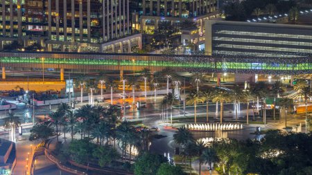 Téléchargez les photos : Dubaï centre-ville nuit timelapse, éclairé bâtiments modernes de luxe et fontaine avec la circulation sur le cercle, paysage urbain futuriste des Émirats arabes unis. Vue aérienne du dessus depuis le gratte-ciel - en image libre de droit