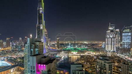 Photo for Dubai downtown cityscape with Burj Khalifa, LightUp light show aerial timelapse from rooftop and fountains. Artificial lake The United Arab Emirates city of Dubai - Royalty Free Image