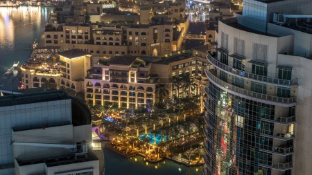 Téléchargez les photos : Dubaï centre-ville nuit timelapse, éclairé bâtiments modernes de luxe et fontaines avec piscine entourée de palmiers, paysage urbain futuriste des Émirats arabes unis. Vue aérienne du dessus depuis le gratte-ciel - en image libre de droit