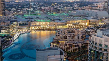 Téléchargez les photos : Vue aérienne de nuit Fontaines dansantes au centre-ville et dans un timelapse de lac artificiel à Dubaï, Émirats arabes unis. Bâtiments éclairés après le coucher du soleil - en image libre de droit