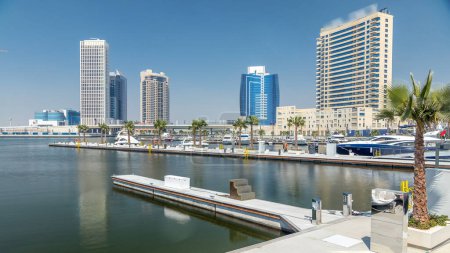panoramische Zeitraffer-Ansicht der Businessbucht und der Innenstadt von Dubai. moderne Wolkenkratzer, die sich in Wasser und blauem Himmel spiegeln. Blick von der Uferpromenade mit Yachten und Booten