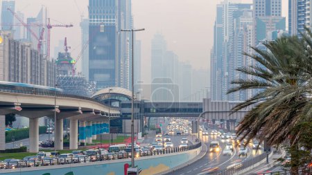 Téléchargez les photos : Trafic sur l'intersection et l'autoroute à la route Sheikh Zayed entouré de gratte-ciel jour à la nuit passage timelapse. Vue d'en haut à Dubaï le soir, Émirats arabes unis - en image libre de droit