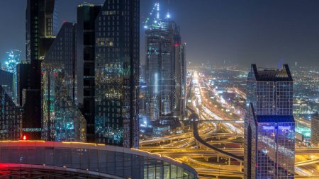 Téléchargez les photos : Dubaï ville skyline nuit timelapse et Sheikh Zayed route carrefour trafic, EAU. Vue aérienne depuis le toit du gratte-ciel avec des tours modernes éclairées - en image libre de droit