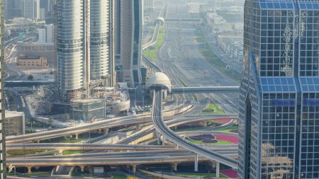 Téléchargez les photos : Trafic sur une intersection achalandée sur l'autoroute Cheikh Zayed timelapse aérien. Vue depuis le toit du gratte-ciel à la soirée ensoleillée avant le coucher du soleil - en image libre de droit