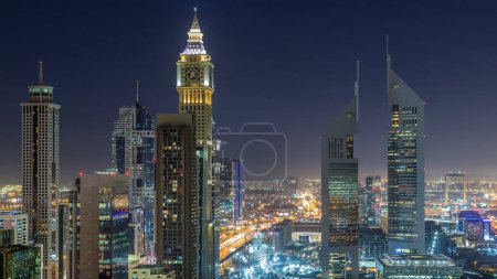 Foto de Vista panorámica de los edificios de Sheikh Zayed Road y el timelapse nocturno DIFC en Dubai, Emiratos Árabes Unidos. Rascacielos más altos iluminados en vista aérea del centro financiero desde arriba - Imagen libre de derechos