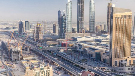 Foto de Dubai skyline centro al atardecer timelapse y el tráfico por carretera cerca de centro comercial y sitio de construcción, Emiratos Árabes Unidos. Vista aérea desde la azotea de rascacielos con torres modernas - Imagen libre de derechos
